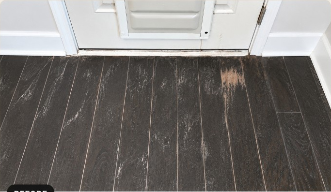 Dark hardwood floor with heavy scratches near a doorway before restoration