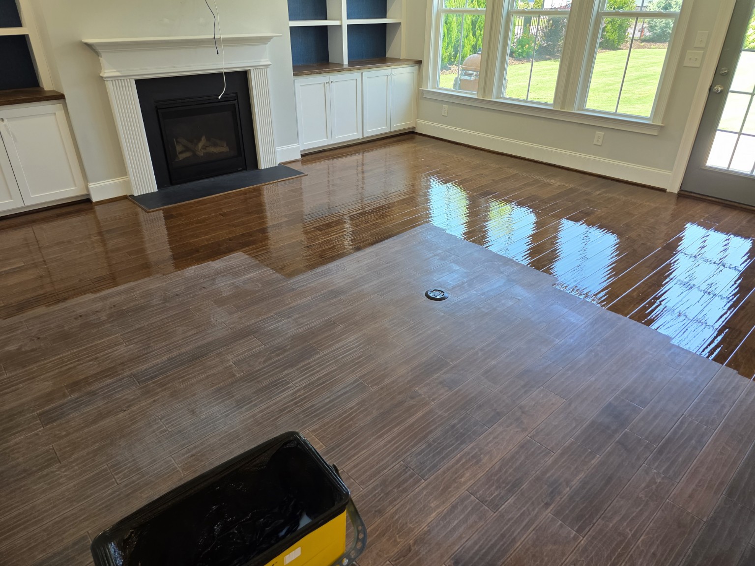 Hardwood floor finish application showing completed and in-progress sections